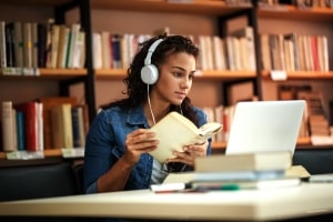 Young Female Student Studying Book and Online on Laptop