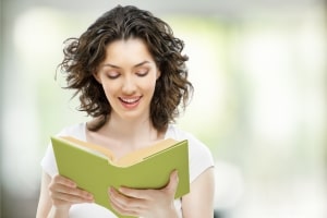 Girl Smiling While Reading a Green Book