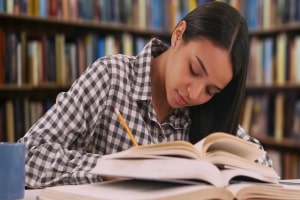 Girl Student in Check Shirt Studying in University Library