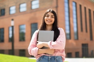 Smiling Student with Laptop in Outdoor College Campus