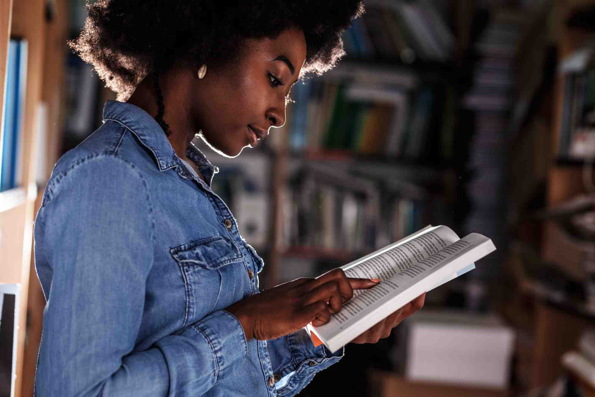 Girl Standing in College Library Reading A Book