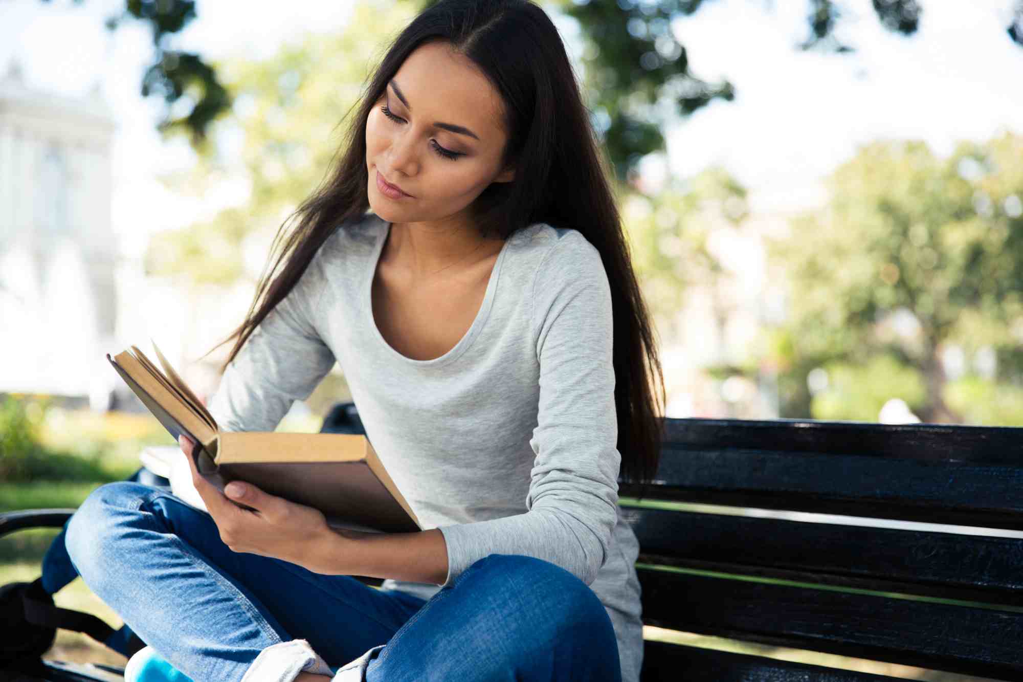 Woman Sitting on Park Bench Reading Book