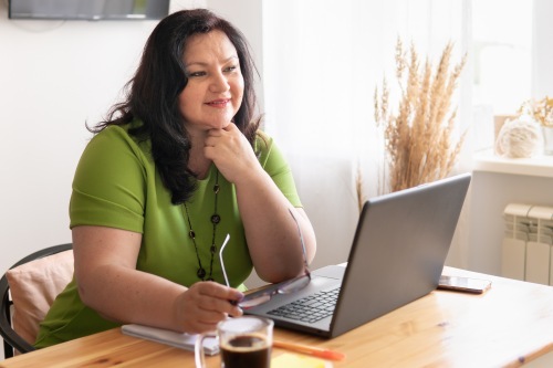 Middle Aged Female attending online mortuary classes on a laptop