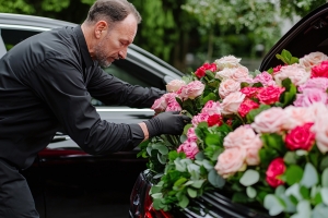 Hearse Driver Adjusting Flowers on The Vehicle