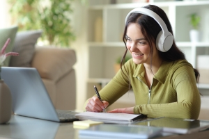 Smiling Female Student Taking Notes in Online Mortuary Science Class