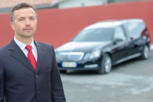An Experienced Funeral Director Standing in Front of Hearse