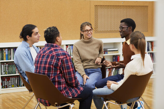 Multi-ethnic group of young people sitting in circle and sharing ideas during class in college
