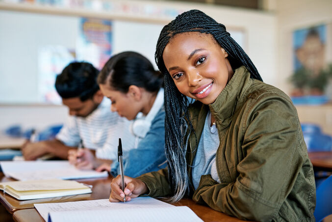 attractive young university student taking notes while sitting in class