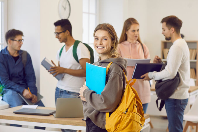 happy smiling beautiful female university student with bag and notebook
