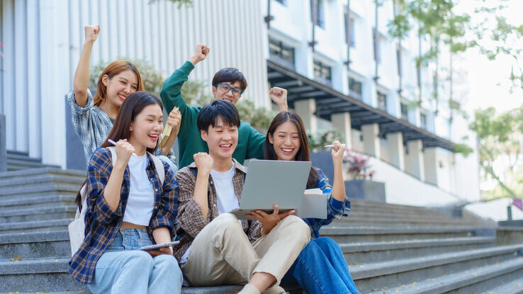 Attractive asian college student using laptop and tablet studying with group of friends together
