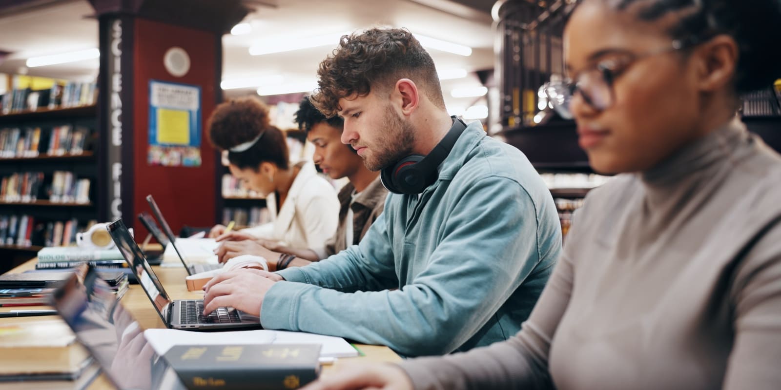 College students working on their laptops in a library.