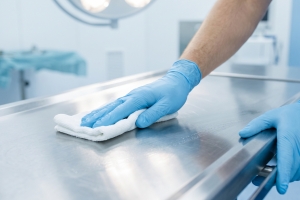 Worker Sanitizing Metal Surface in Mortuary Room